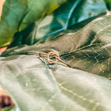 Naut & Chain Heart Knot Ring featuring a delicate intertwined heart design in silver on a plain background.
